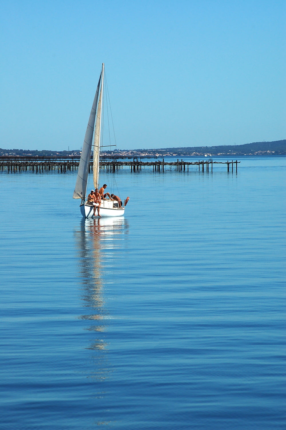 a sailboat with three people on it in the water