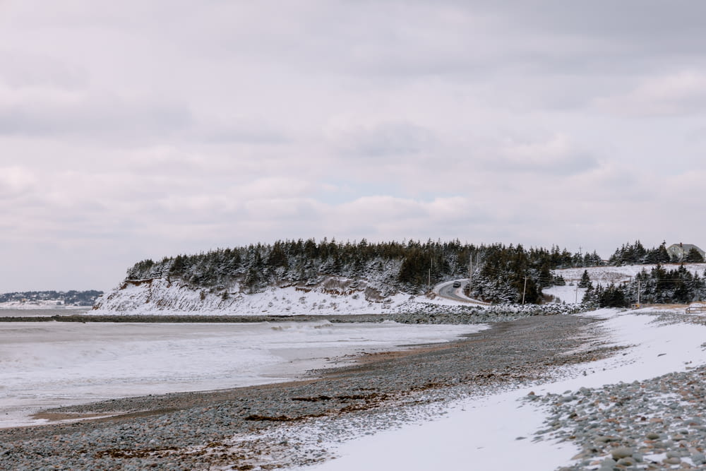 a snow covered beach next to a large body of water