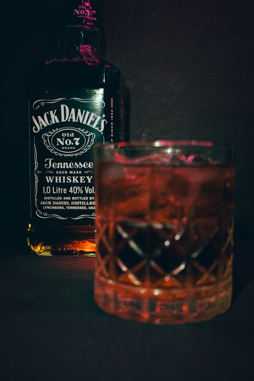 a glass of whiskey next to a bottle of jack daniels