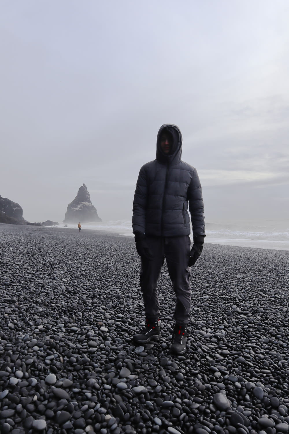 um homem de pé em uma praia rochosa ao lado do oceano
