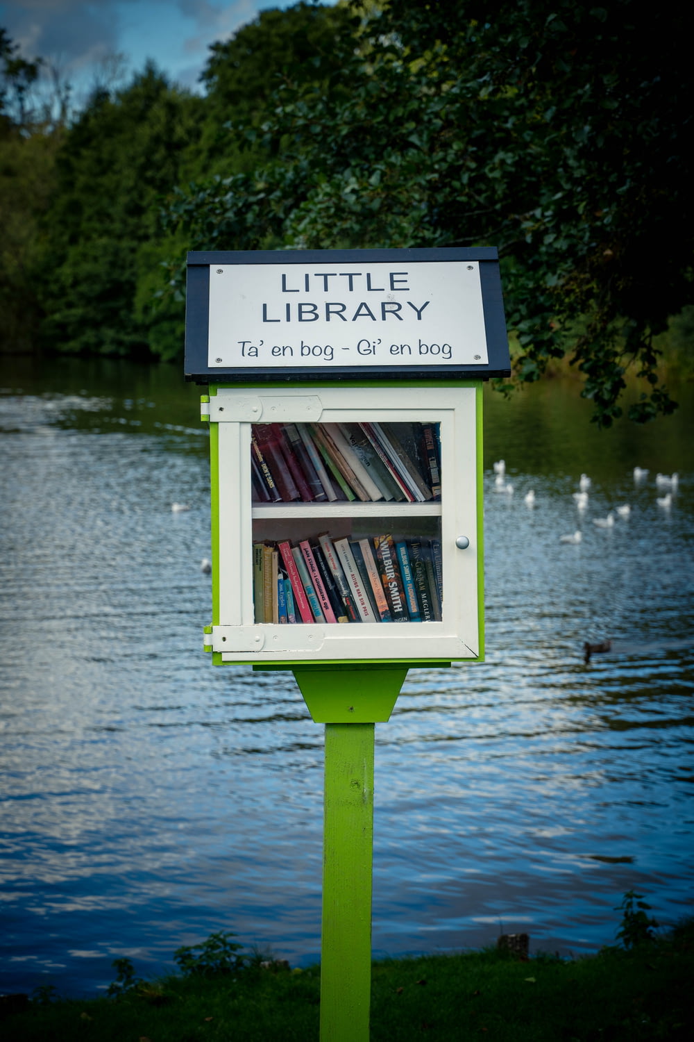 a sign with a book shelf in front of a lake