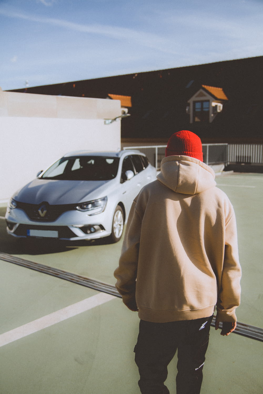 a person in a hoodie walking towards a car