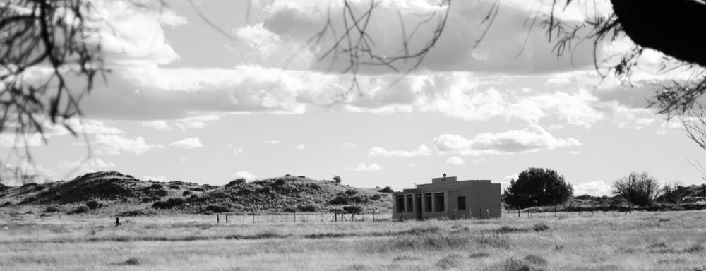ein Schwarz-Weiß-Foto eines Hauses mitten auf einem Feld
