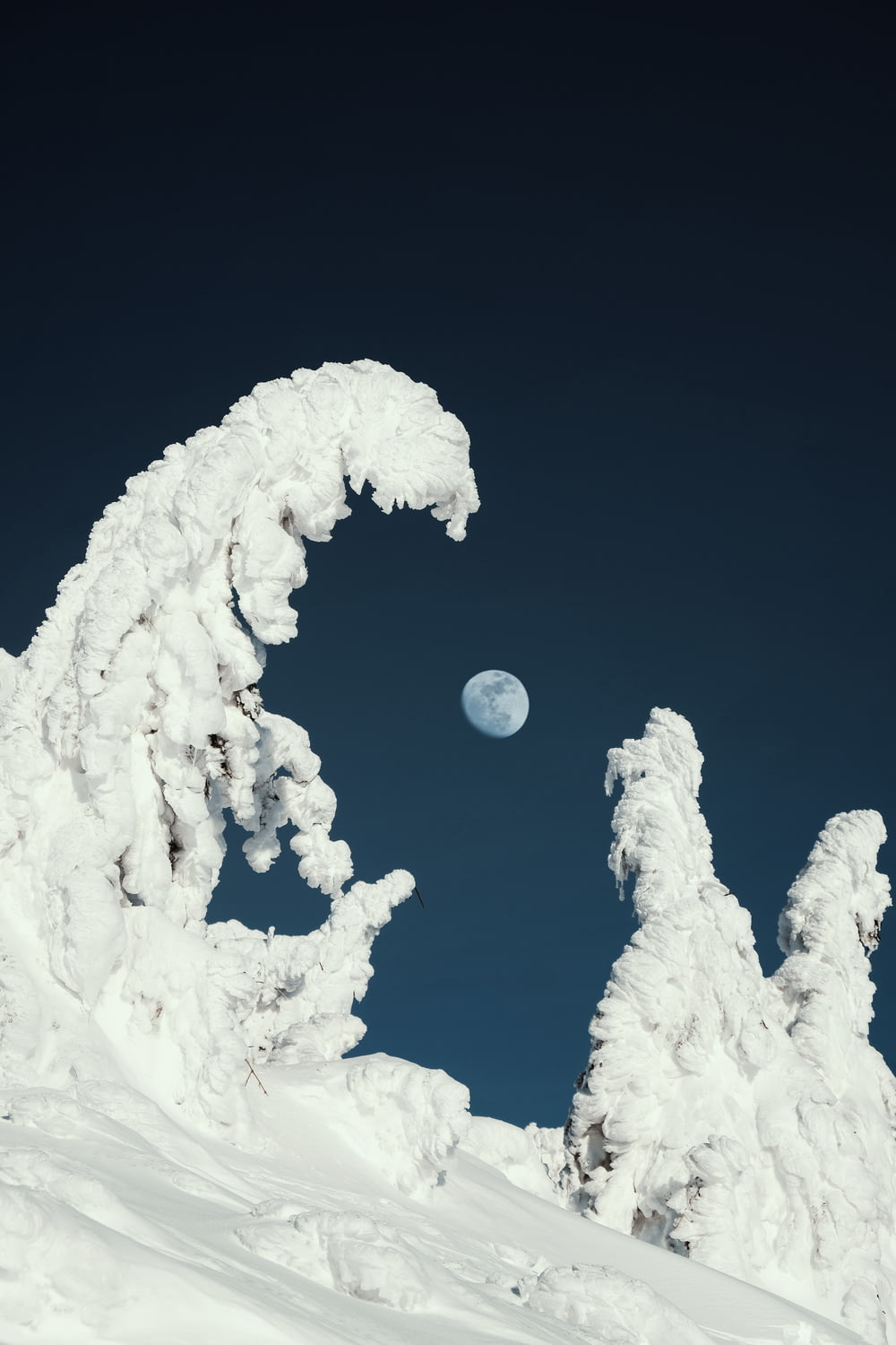 a snow covered mountain with a full moon in the sky