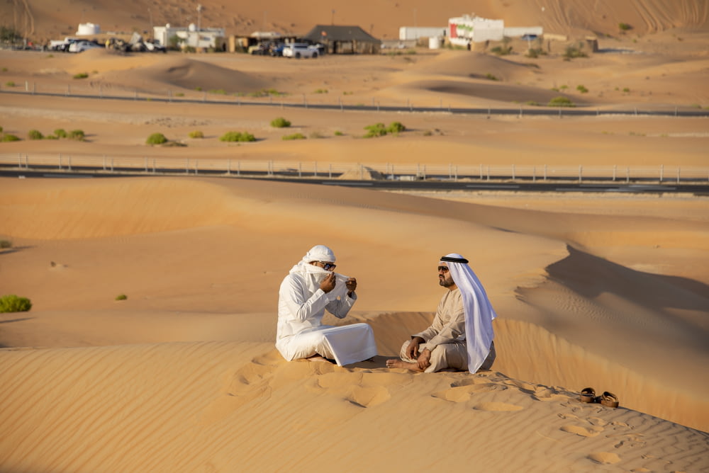 Un par de hombres sentados en la cima de un desierto