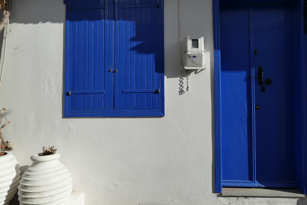 Un edificio blanco con persianas azules y un teléfono