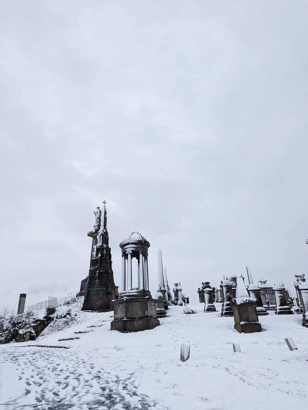 a snow covered cemetery with a clock tower in the background