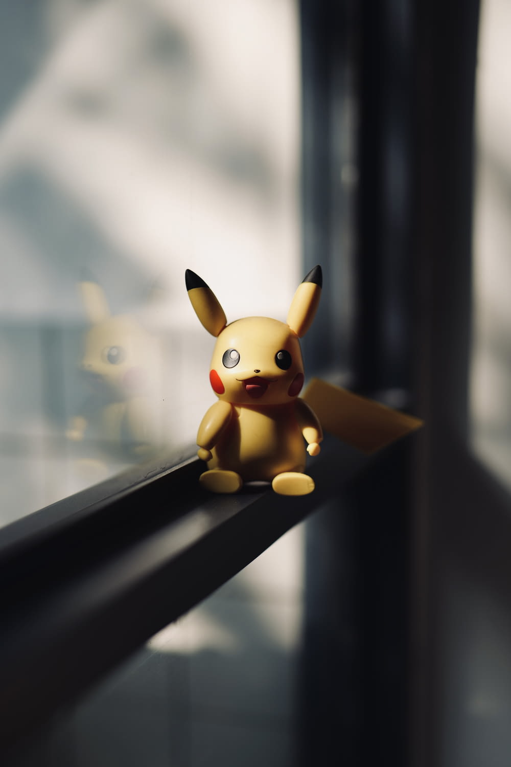 Un Pikachu jouet assis sur le rebord d’une fenêtre