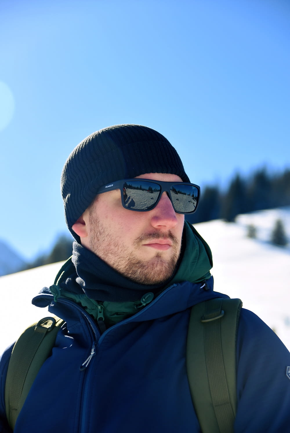 a man with a backpack and sunglasses on in the snow