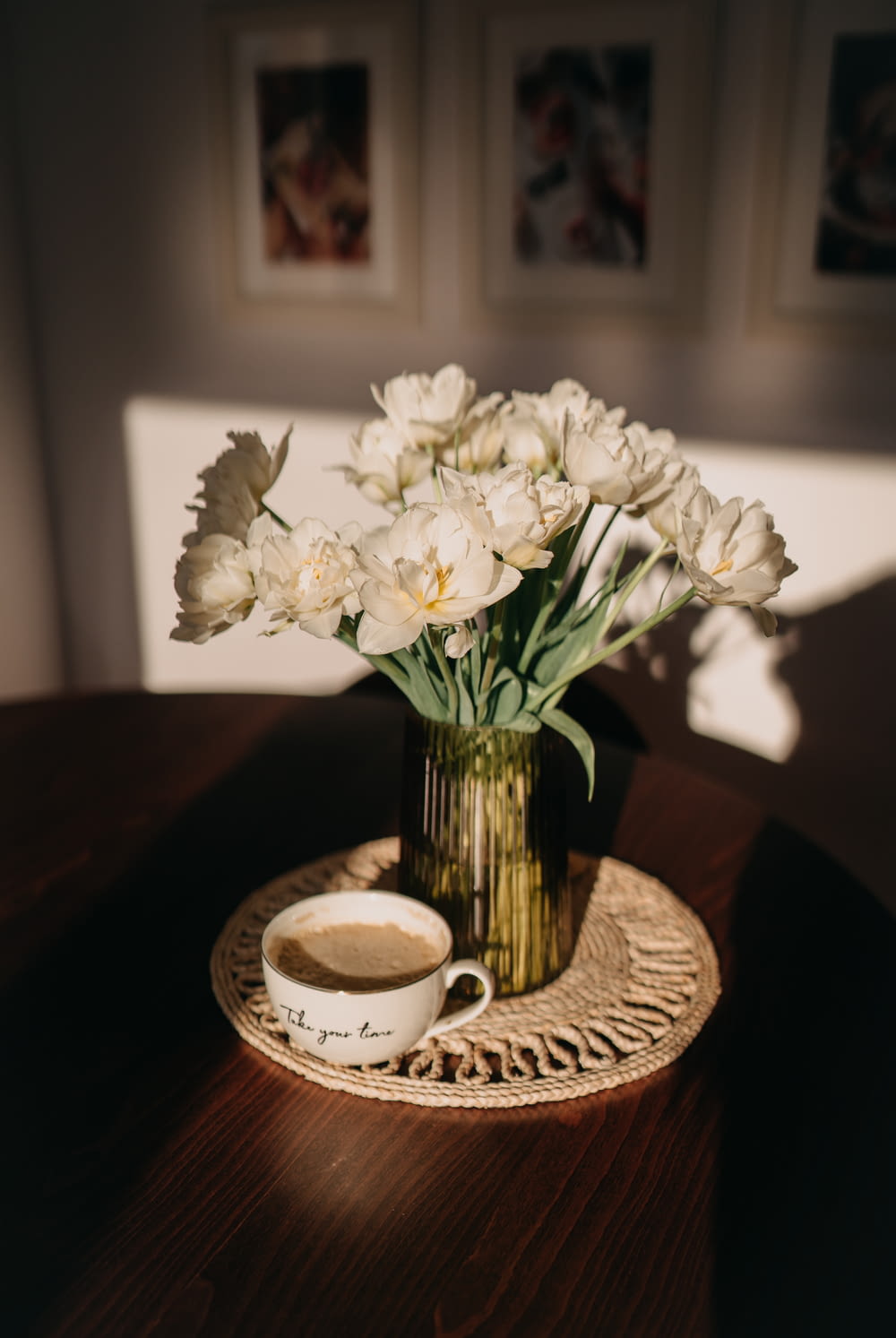 a vase of flowers on a table with a cup of coffee