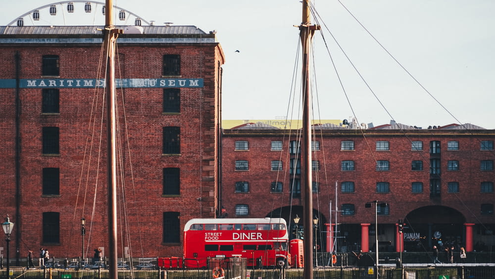 a red double decker bus parked in front of a building