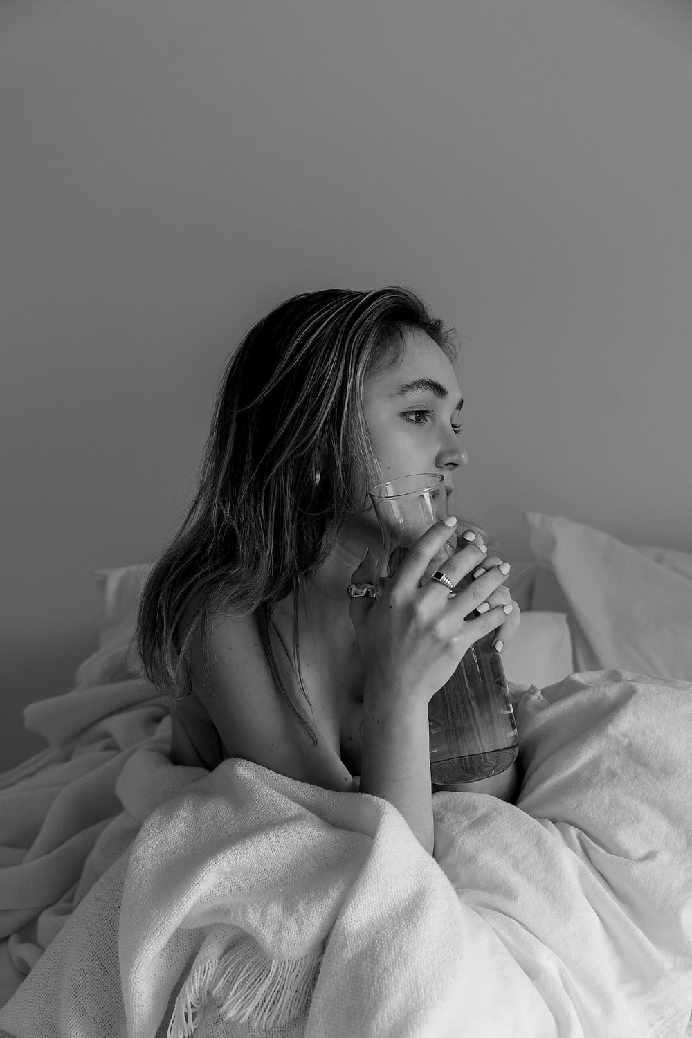 a woman laying in bed drinking from a glass