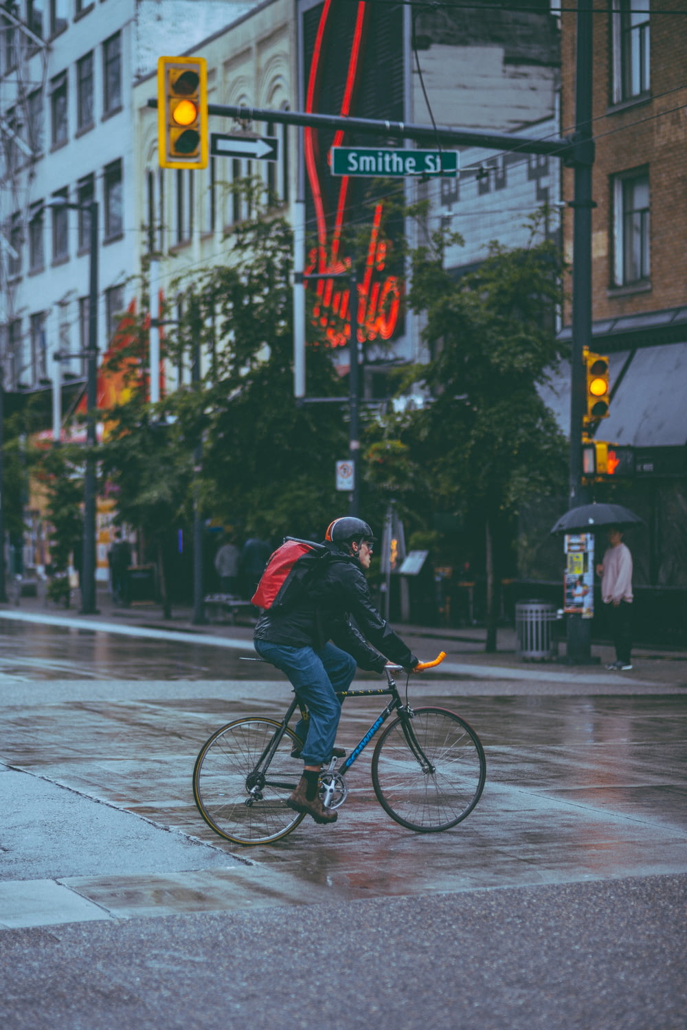 雨に濡れた通りを自転車で走る男