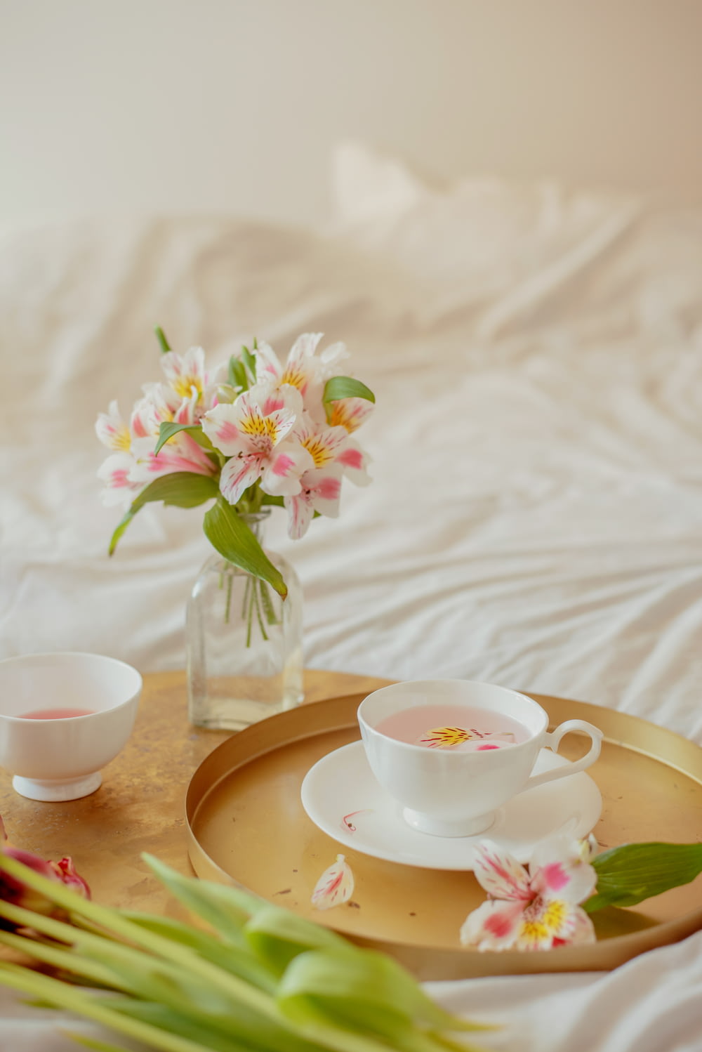 a tray with a cup and saucer and a vase with flowers