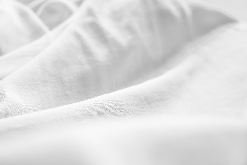 a black and white photo of a bed with white sheets
