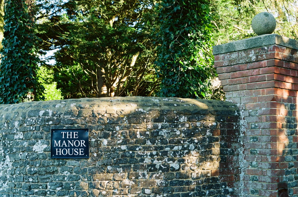 a brick wall with a sign that says the manor house