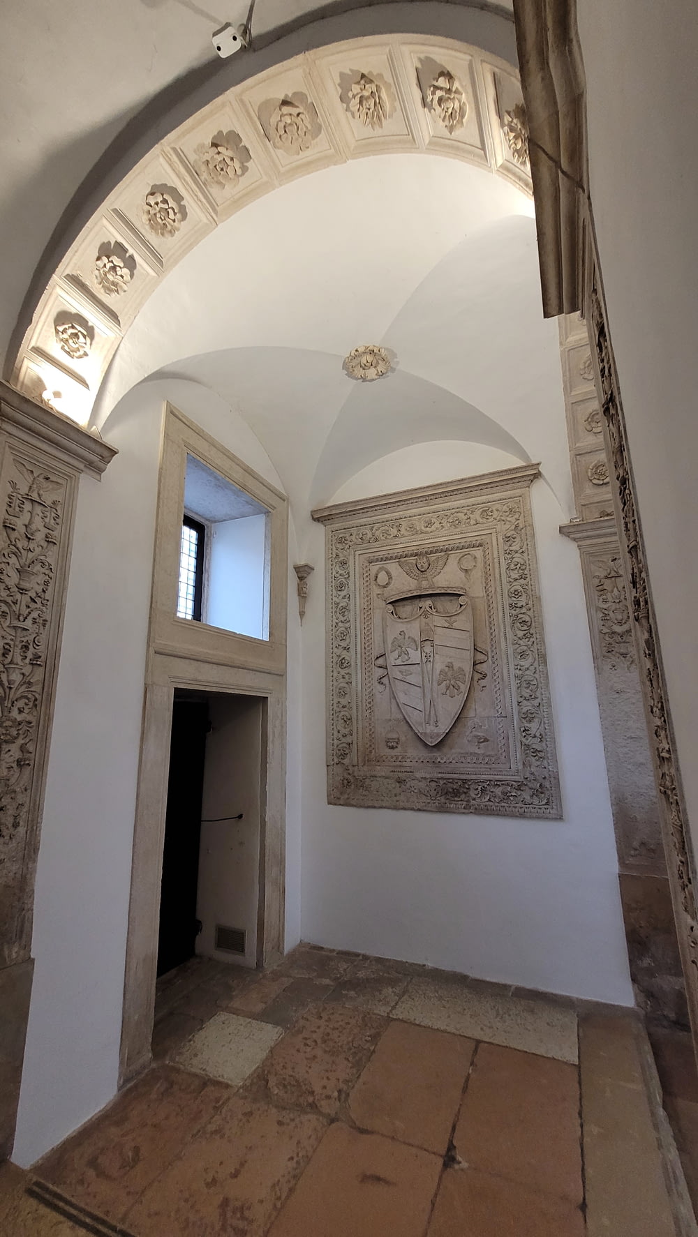 an archway leading to a room with a coat of arms on the wall