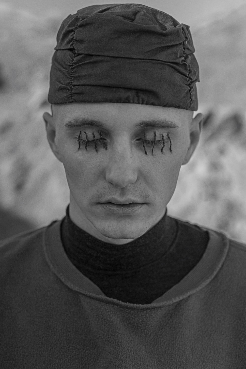 a black and white photo of a man with eye makeup