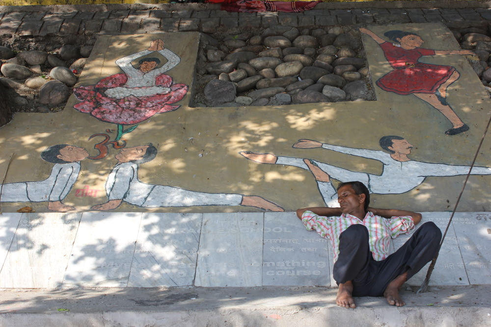 a woman sitting on the ground in front of a mural