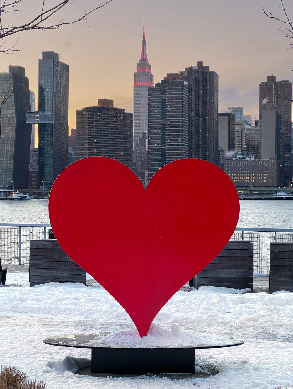 a large red heart sculpture in front of a city skyline