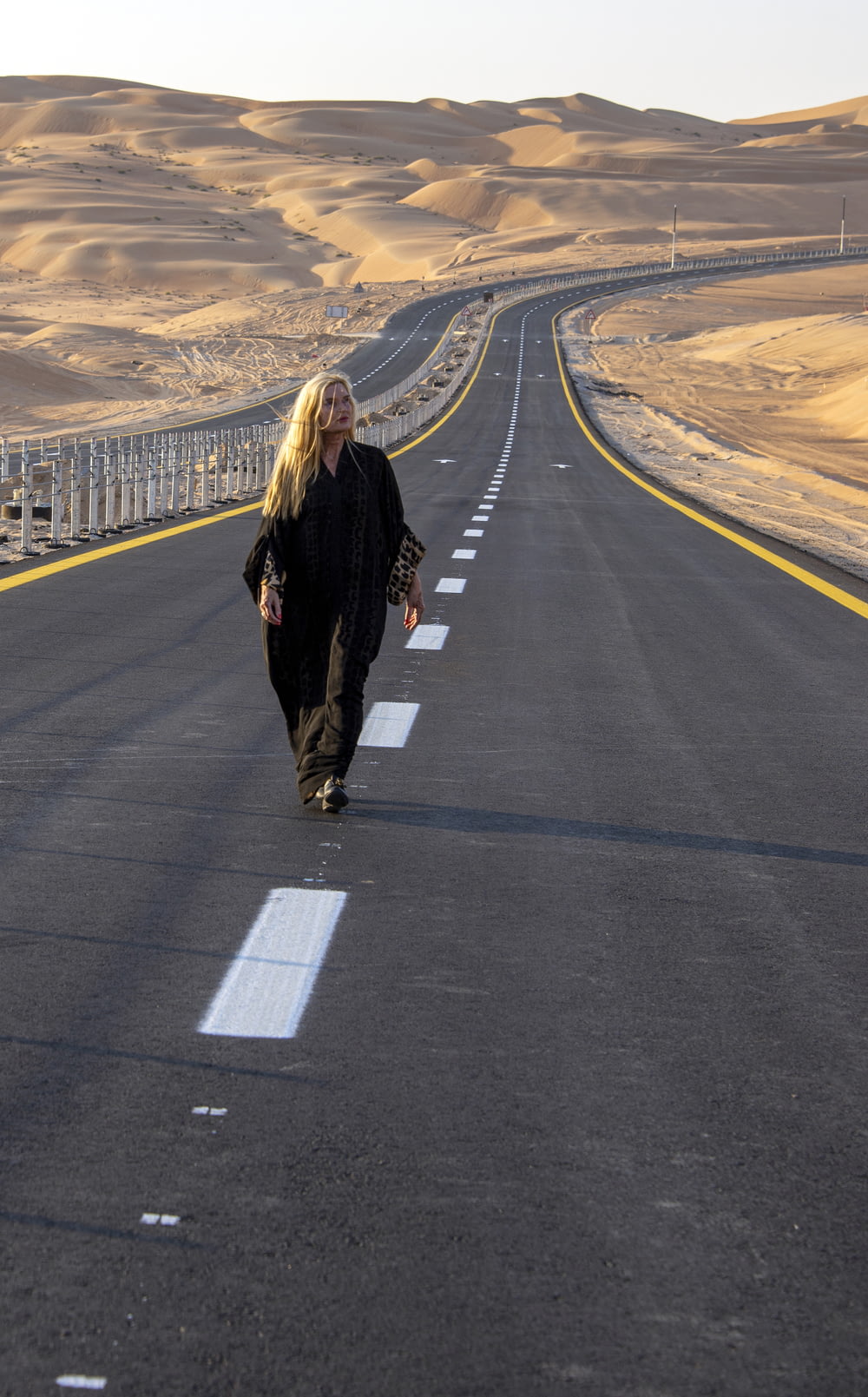 Una mujer caminando por el medio de una carretera