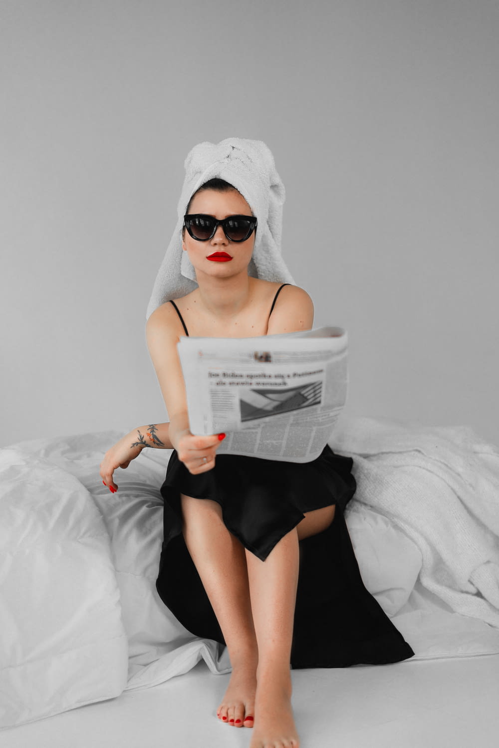 a woman sitting on a bed reading a newspaper