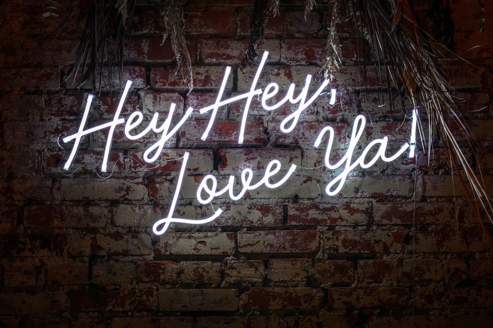 a brick wall with a neon sign that says hey hey love you