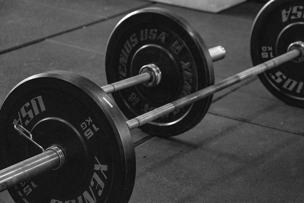 a black and white photo of a barbell in a gym