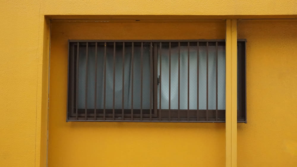 a yellow building with a window with bars on it