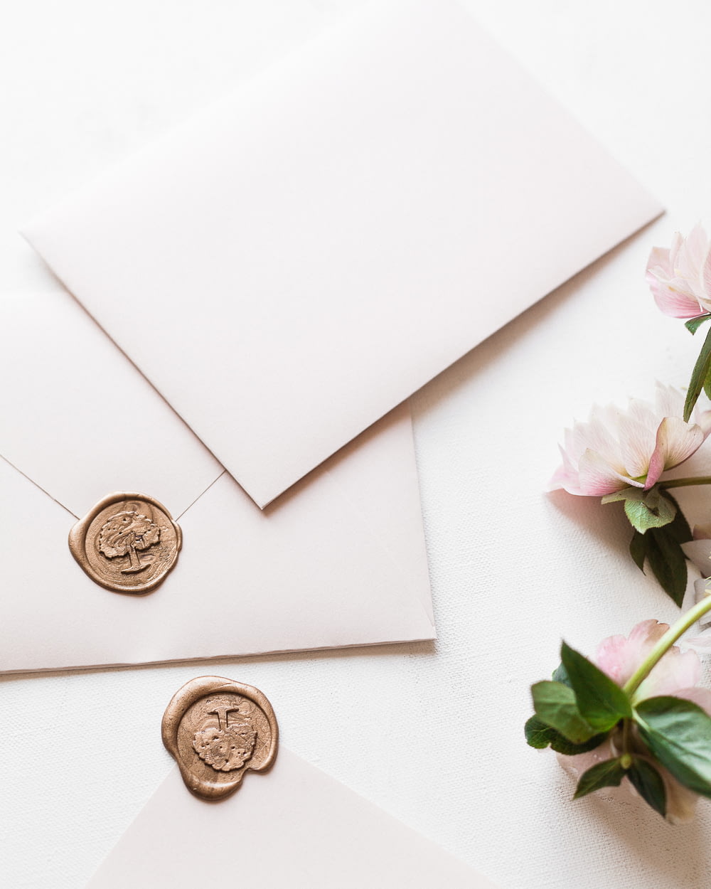 a white envelope with a wax stamp and some pink flowers