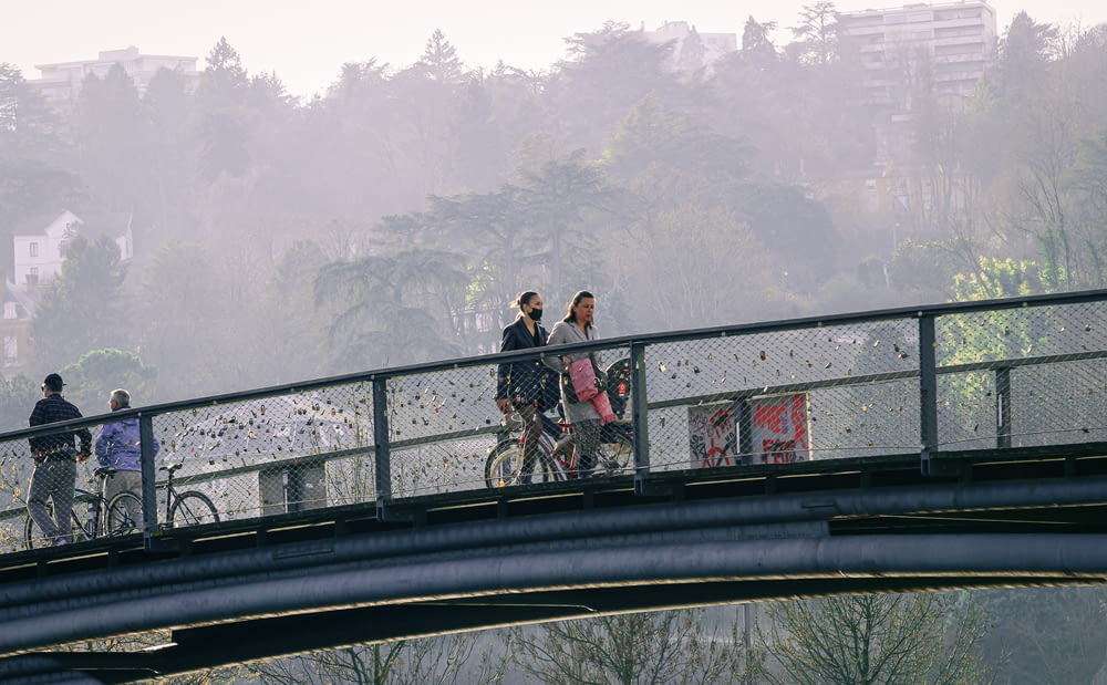 a group of people riding bikes across a bridge