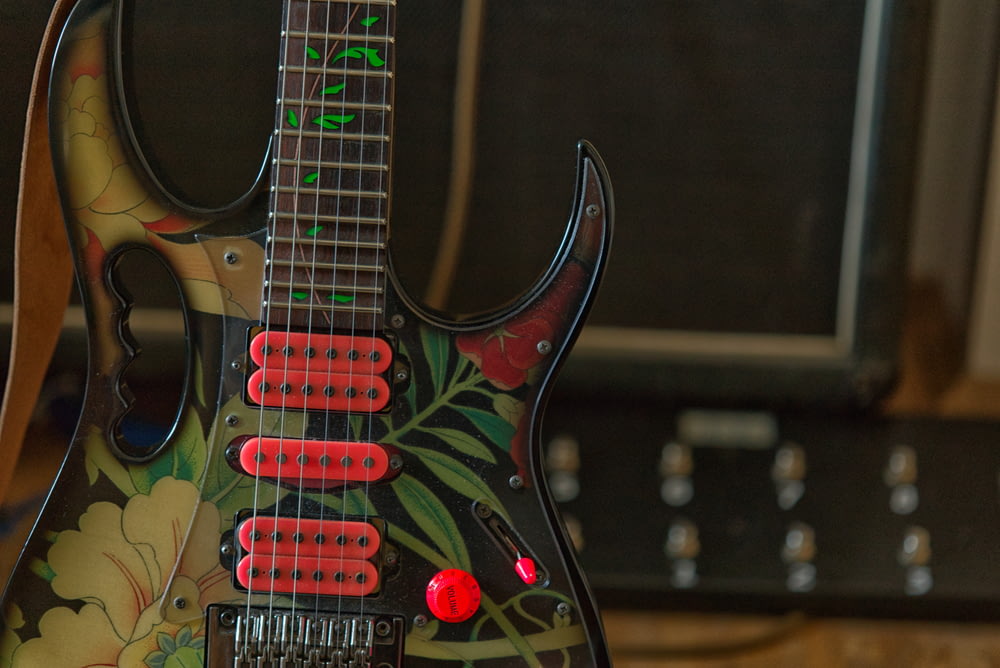a black guitar with red knobs sitting on top of a table