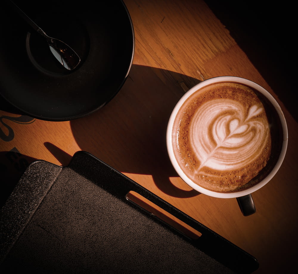 Ein Cappuccino auf einem Tisch mit einem Löffel daneben