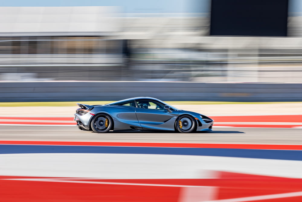 a blue sports car driving on a race track