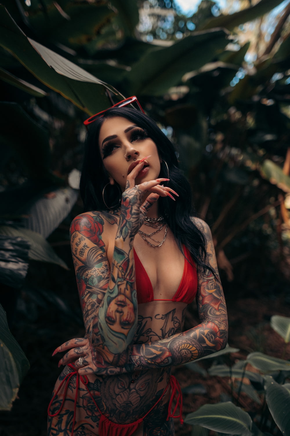 a woman in a red bikini with tattoos smoking a cigarette