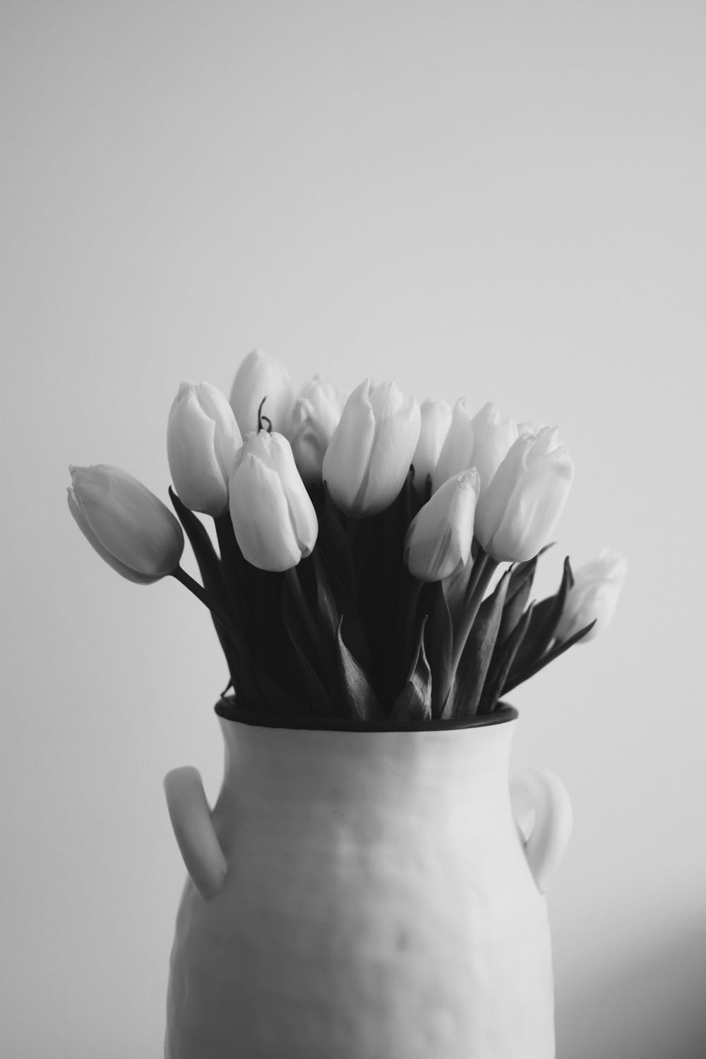 a white vase filled with lots of white flowers