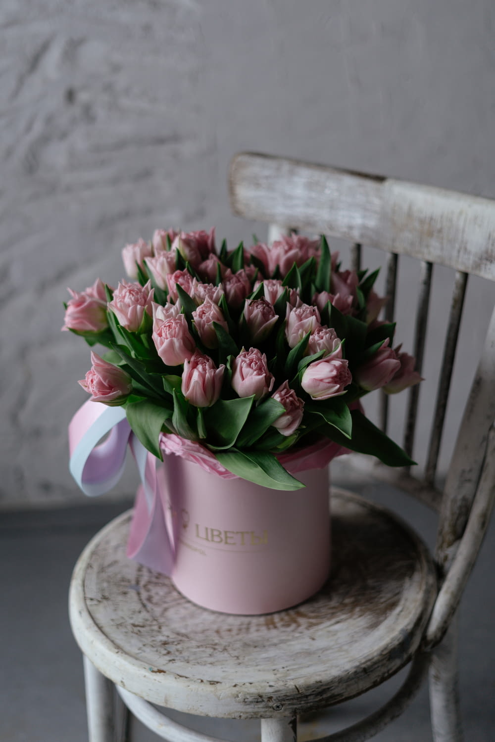 a pink flower pot sitting on top of a wooden chair