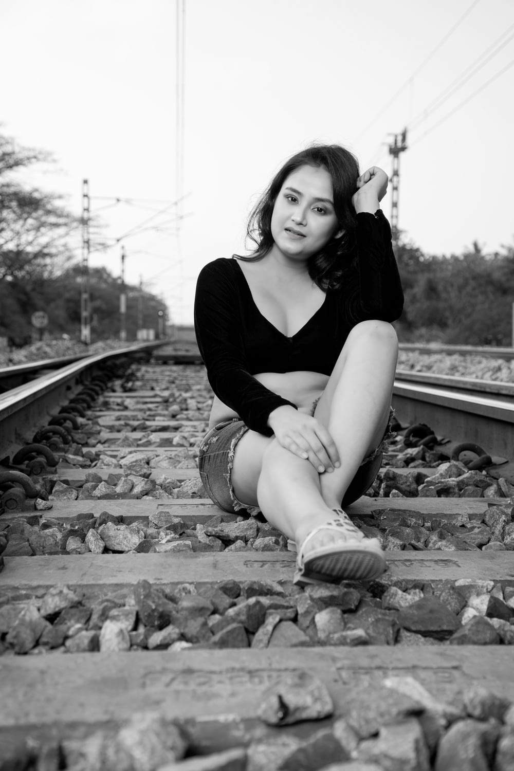 a woman sitting on train tracks posing for a picture