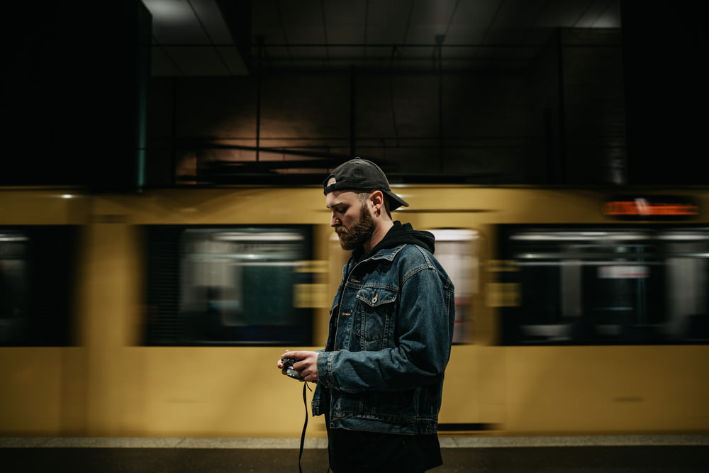 a man standing in front of a train holding a cell phone