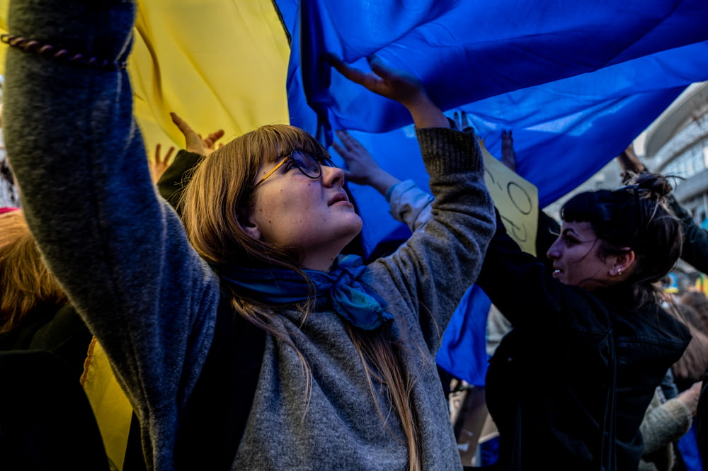 a woman holding up a blue and yellow flag