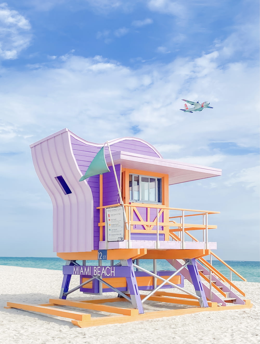 a lifeguard stand on the beach with a plane in the background