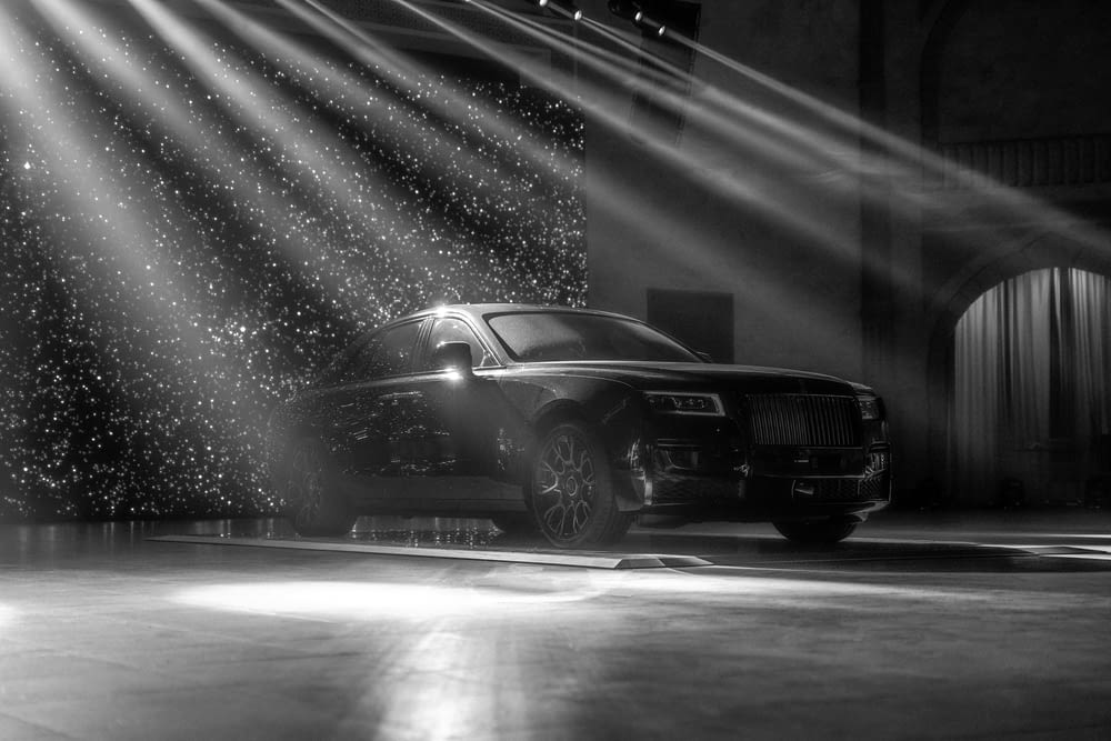 a black and white photo of a rolls royce parked in a garage