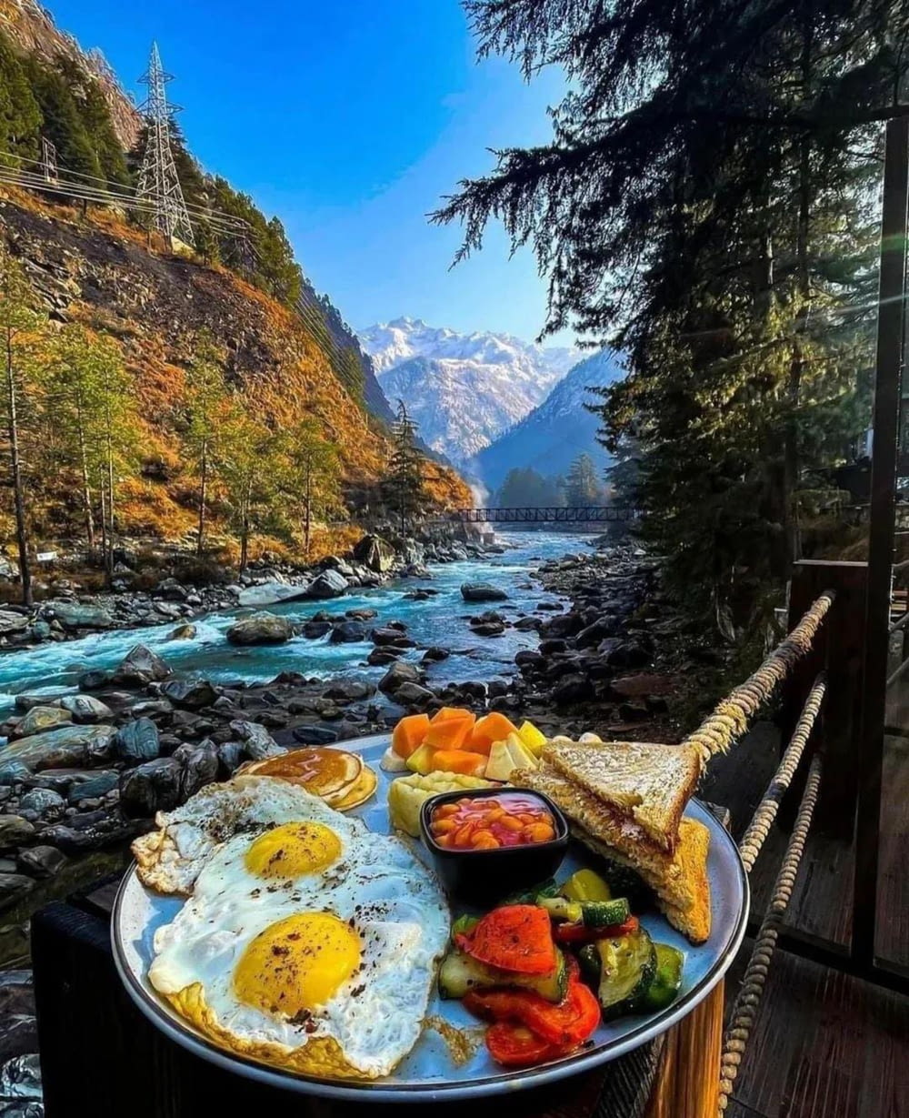 um prato de comida sentado em cima de uma mesa ao lado de um rio
