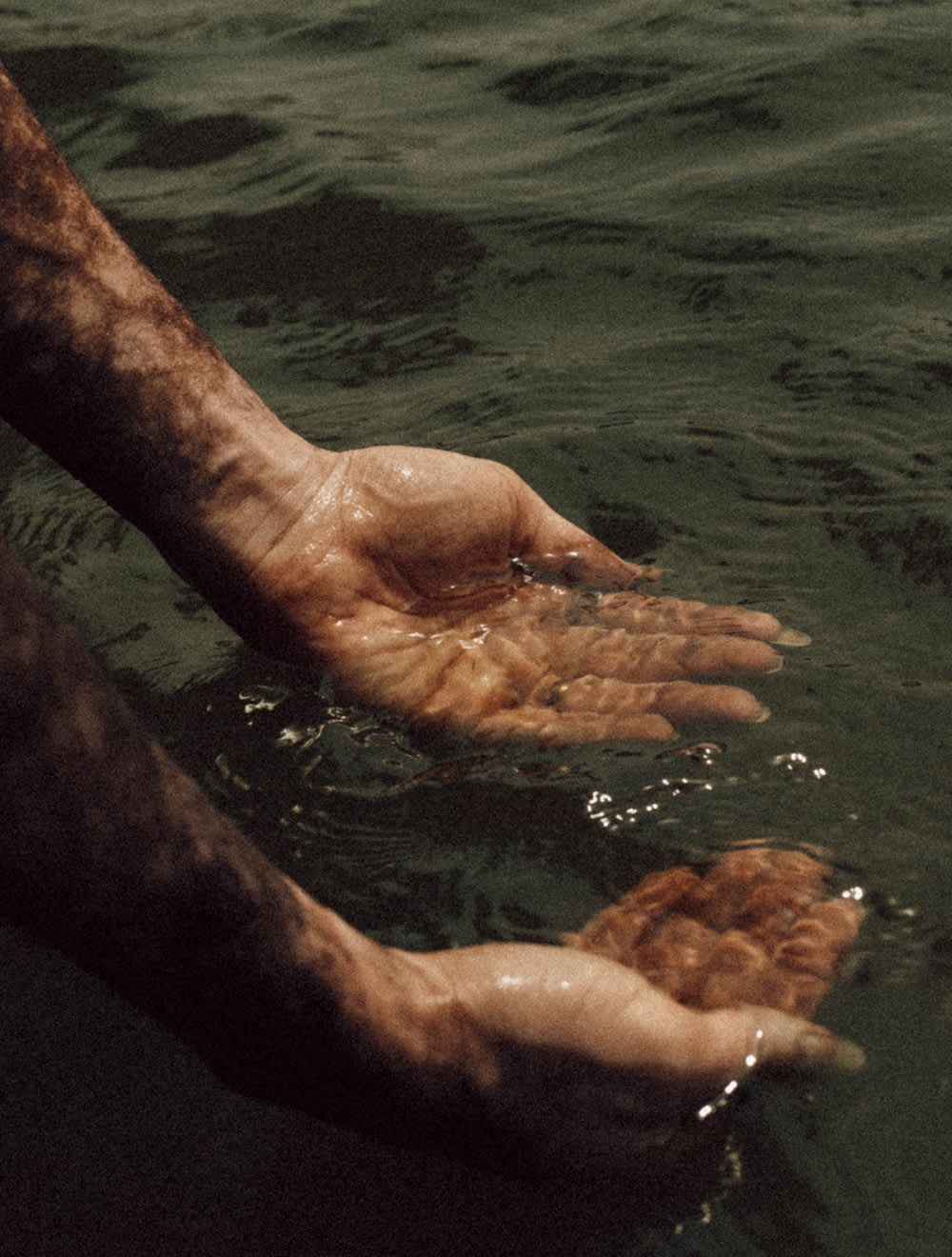 a hand reaching for something in the water