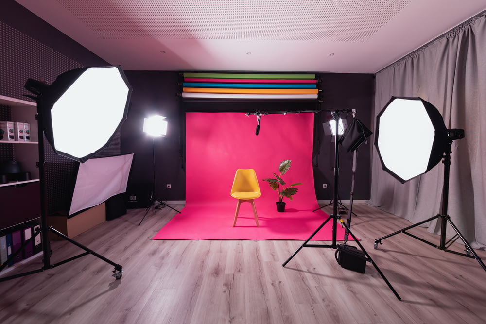 a photo studio with a pink backdrop and a yellow chair