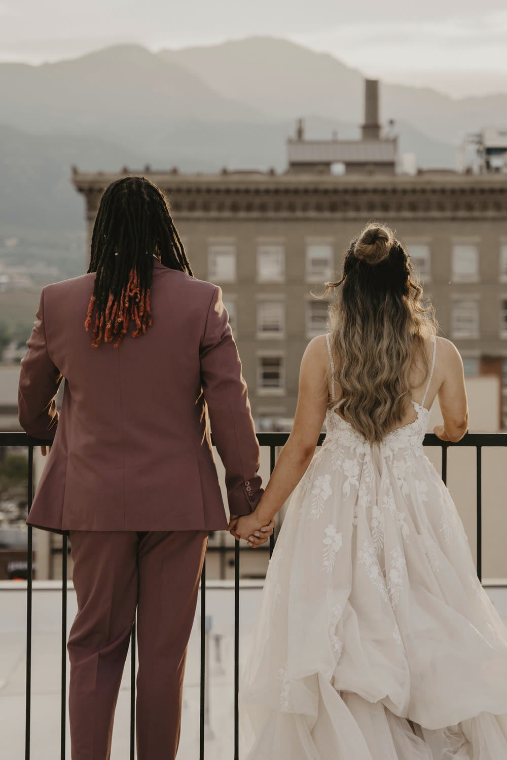 a bride and groom hold hands as they stand on a balcony