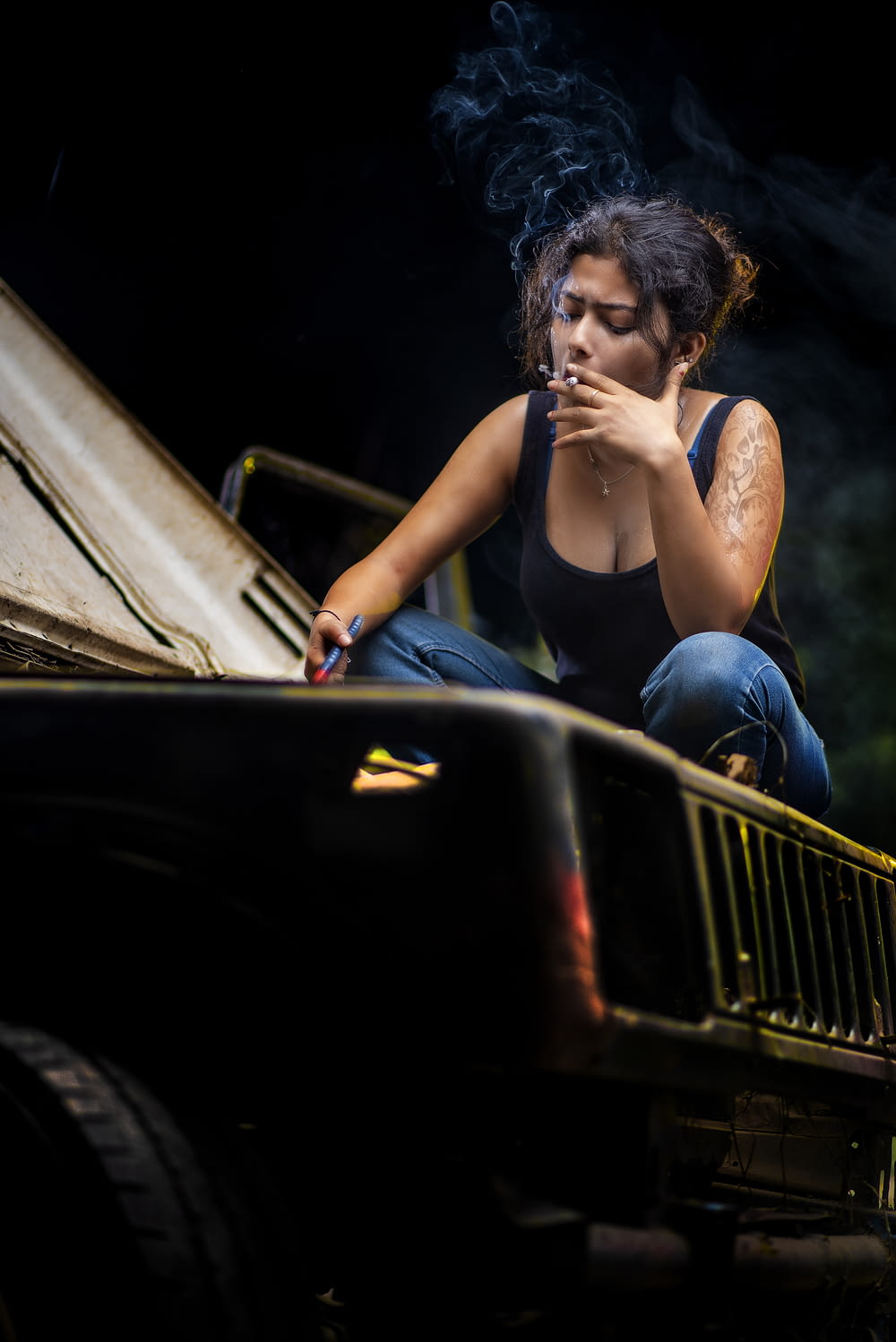 a woman smoking a cigarette sitting on the back of a truck