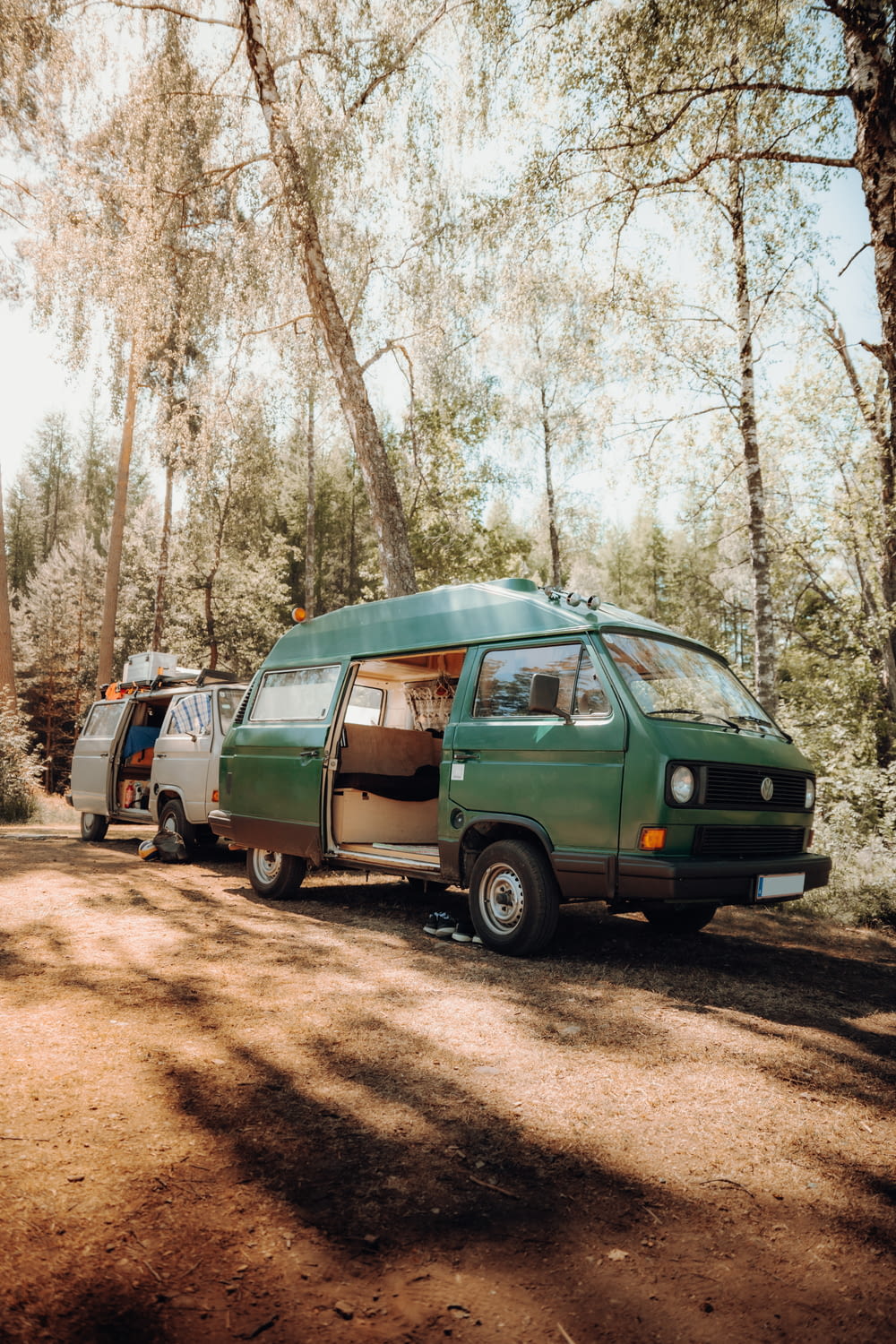 a couple of vans parked next to each other in a forest