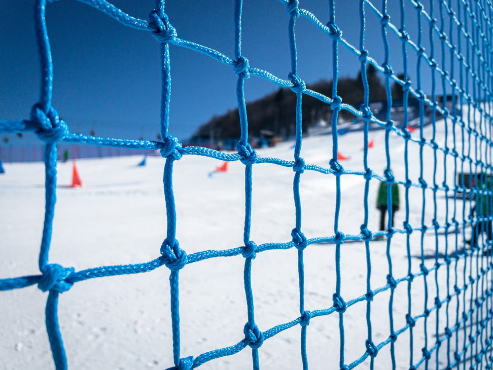 a blue net on the side of a snow covered ski slope