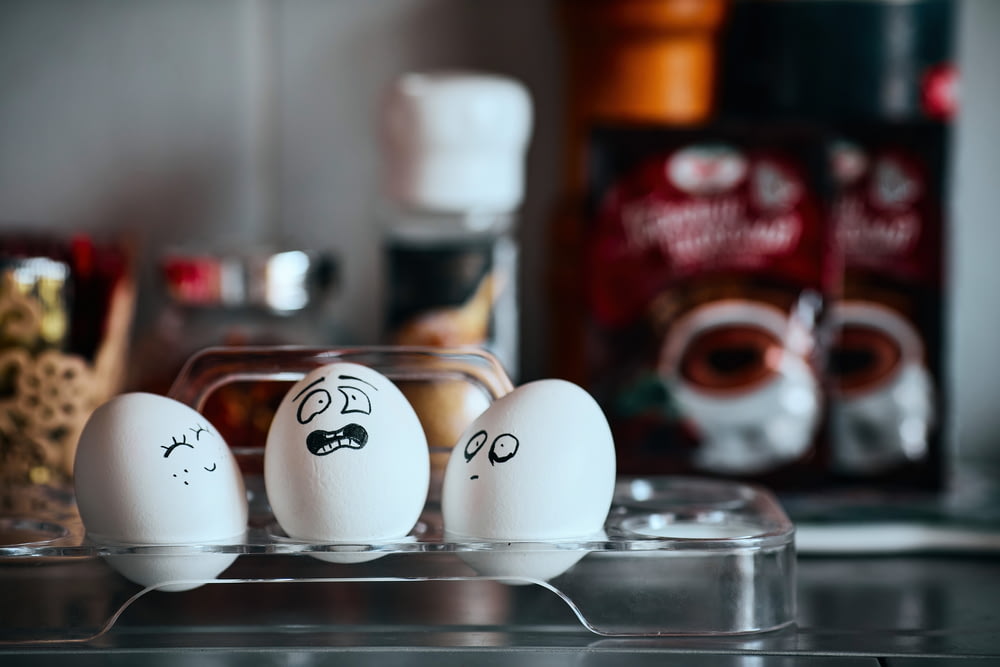 three eggs with faces drawn on them sitting on a counter